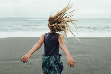 Girl running towards the sea with hair blowing in the wind