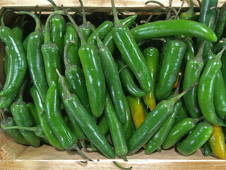 High angle close-up view of a box with fresh green pepperoni displayed for sale at a grocery market