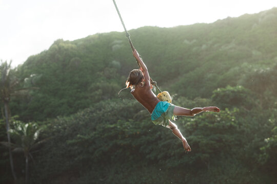 Boy rope swinging in Kauai, Hawaii. 