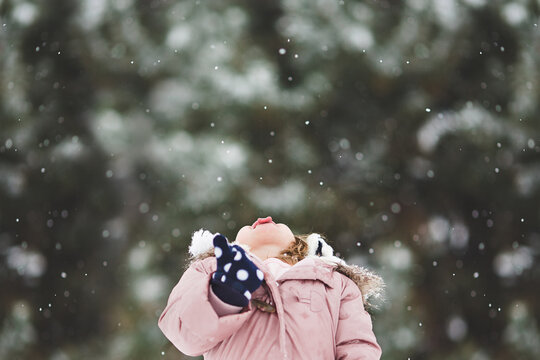 Little girl catching snowflakes with tongue 
