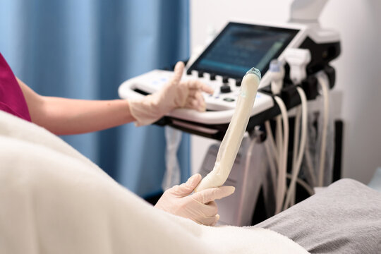 A gynecologist holds in his hand a transvaginal ultrasound scanner with a gel for vaginal examination of a woman. Ultrasound of the pelvic organs. Close-up, selective focus. Medical equipment concept.