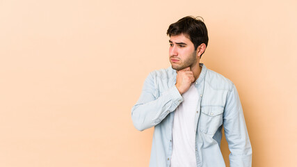 Young man isolated on beige background suffers pain in throat due a virus or infection.