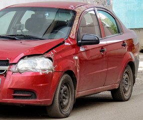 Fototapeta na wymiar A dented red car. The consequence of a small accident on the road.