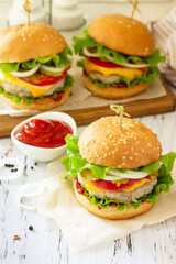 Delicious burgers, hamburger sandwich with cutlet, cheese, bacon and tomatoes on a wooden table. Copy space.