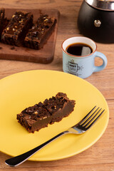 plate with a slice of brownie, a coffee maker and a cup of coffee