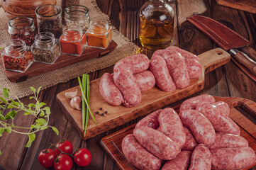 Raw brazilian sausages on the wooden board with ingredients - Linguiça churrasco