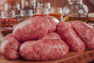 Raw brazilian sausages on the wooden board with ingredients - Linguiça churrasco