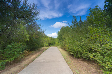 Plakat A concrete path in a Texas urban nature reserve on a sunny September day.