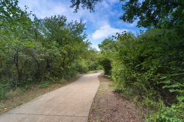 Fototapeta na wymiar A concrete path in a Texas urban nature reserve on a sunny September day.
