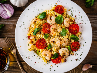 Pasta with prawns and vegetables highly seasoned on wooden table