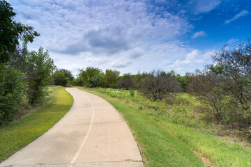 A concrete path in a Texas urban nature reserve on a sunny September day.