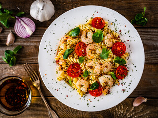 Pasta with prawns and vegetables highly seasoned on wooden table