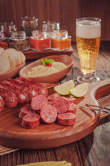 Grilled Sausage skewer on wooden board with beer, bread and farofa - Brazilian barbecue