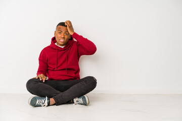 Young latin man sitting on the floor isolated being shocked, she has remembered important meeting.