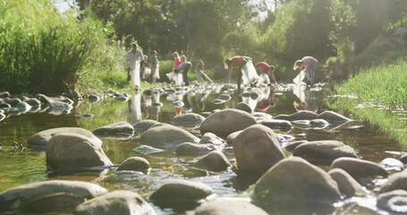 Mid adults volunteering during river clean-up day - Powered by Adobe