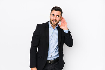 Fototapeta premium Young caucasian business man against a white background isolated trying to listening a gossip.