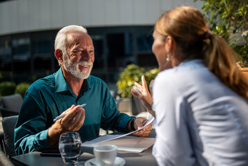 Mature man signing contract with businesswoman