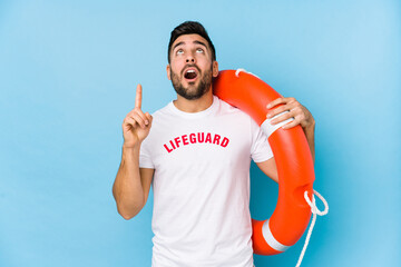 Young handsome lifeguard man isoalted pointing upside with opened mouth.