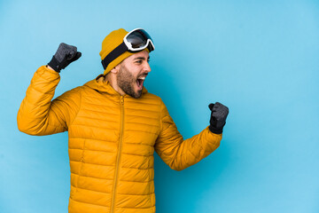 Young skier caucasian man isolated raising fist after a victory, winner concept.