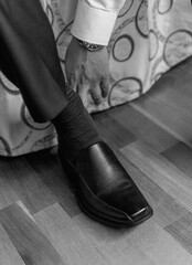groom putting on shoes, black and white photo