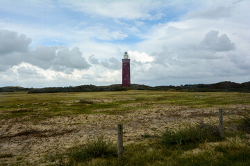 Fototapeta na wymiar Westhoofd lighthouse in Ouddorp in the Netherlands, in a green landscape and a barbed wire