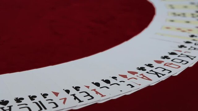 Dealer is Making Fan With Poker Cards in Casino. Croupier Spreading The Deck at Poker Game on Red Table
