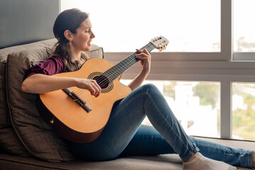 Happy woman playing guitar at home