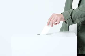 選挙の投票箱に投票用紙を入れる若い男性の手
