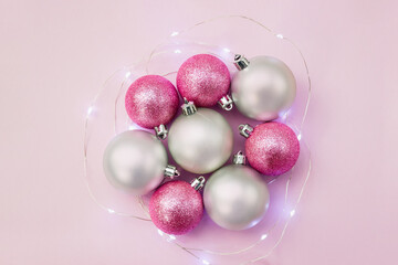 Silver and pink balls surrounded by Christmas light garland. New Year's decor for the home. Selective focus. Copy space