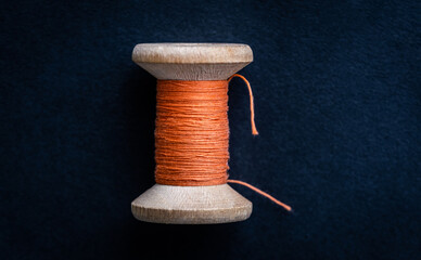 Close up view of orange retro thread on wooden bobbin