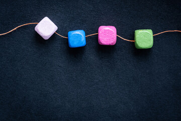 Bright wooden cube beads on thread macro with copy space