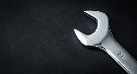 Metallic hand wrench on dark background with copy space