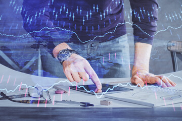 Double exposure of man's hands holding and using a digital device and forex graph drawing. Financial market concept.