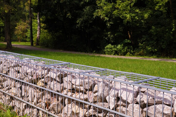 A fragment of a fence made of gabions. Separation of the street from the park area.