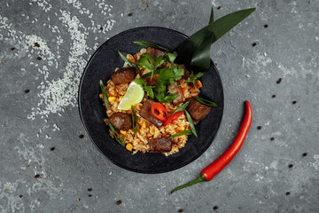 Fried rice with beef and vegetables on a gray textured background