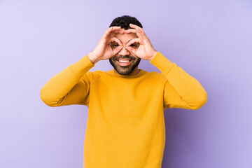 Young mixed race arabic man isolated showing okay sign over eyes