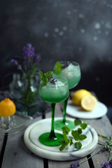Sparkling Woodruff Drink in a glass . green woodruff drink with ice cubes on black background.