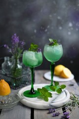 Sparkling Woodruff Drink in a glass . green woodruff drink with ice cubes on black background.