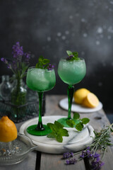 Sparkling Woodruff Drink in a glass . green woodruff drink with ice cubes on black background.