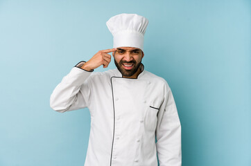 Young latin chef man isolated showing a disappointment gesture with forefinger.