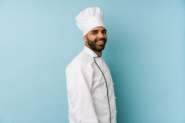 Young latin chef man isolated looks aside smiling, cheerful and pleasant.