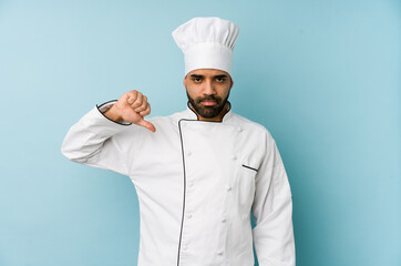 Young latin chef man isolated showing a dislike gesture, thumbs down. Disagreement concept.