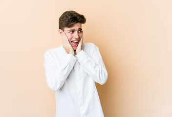 Young caucasian man isolated on beige background scared and afraid.