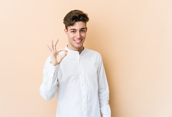 Young caucasian man isolated on beige background cheerful and confident showing ok gesture.