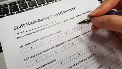 A hand holding a staff well-being questionnaire