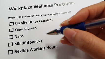 A hand holding a pen, preparing to choose the workplace wellness programs that best suits