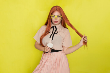 Red haired woman with glasses and office clothing holding cup of coffee or tea