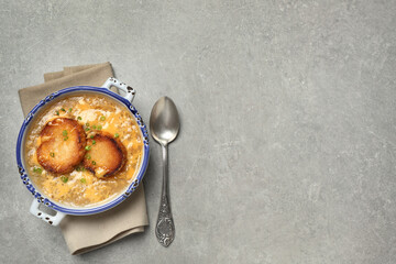 Tasty homemade french onion soup served on grey table, flat lay. Space for text