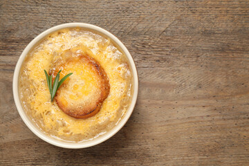 Tasty homemade french onion soup on wooden table, top view. Space for text