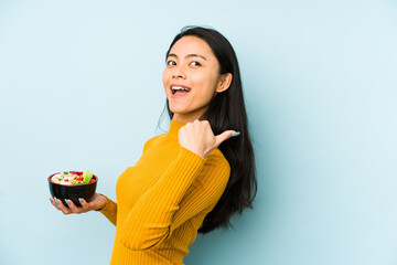 Young chinese woman holding noodles isolated raising fist after a victory, winner concept.